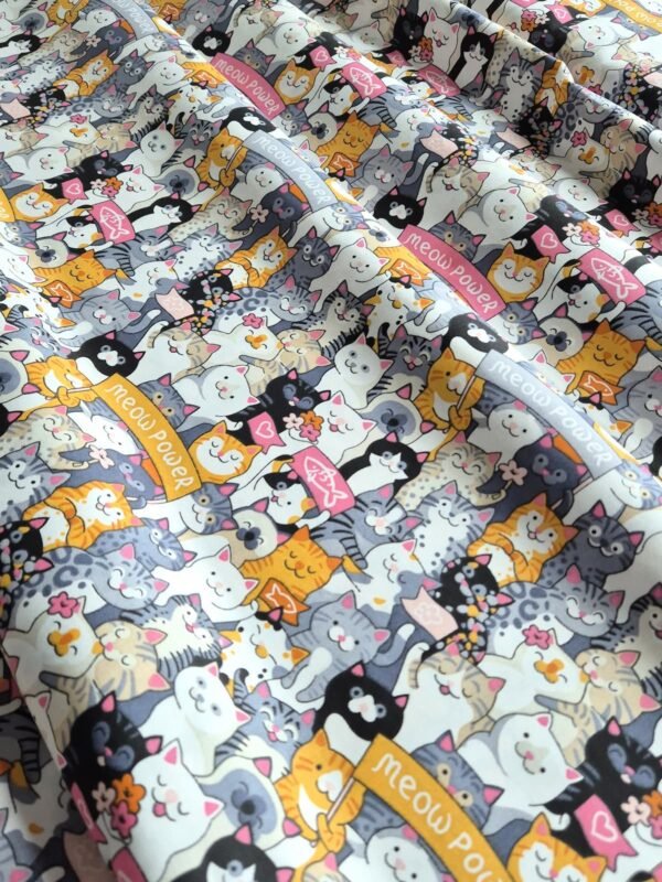 Tela sarga con estampado de caras de gatos de colores dispuesta en forma de olas