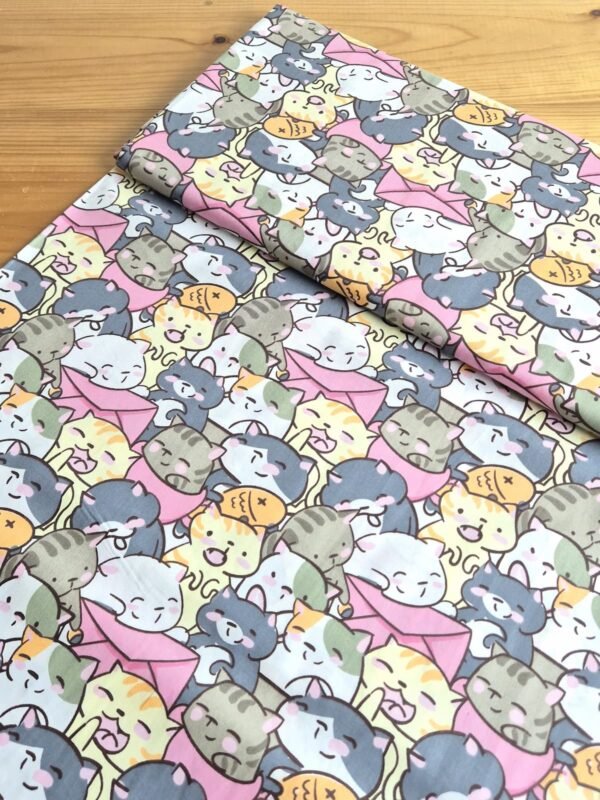 Tela sarga con estampado de gatos kawaii en tono rosa vista en ángulo de 45 grados