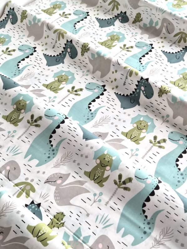 Tela sarga con estampado de dinosaurios y plantas verdes dispuesta en forma de olas