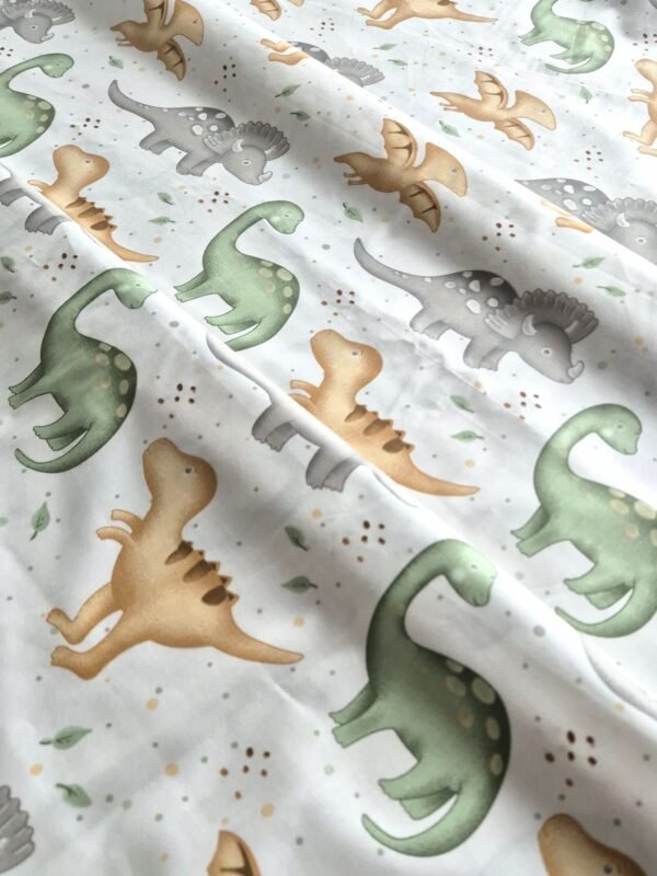 Tela sarga con estampado de dinosaurios variados en tonos pastel dispuesta en forma de olas