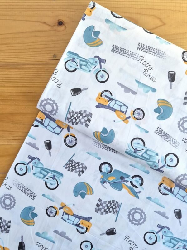 Vista superior de tela sarga con estampado de motos y banderas de carreras sobre fondo claro