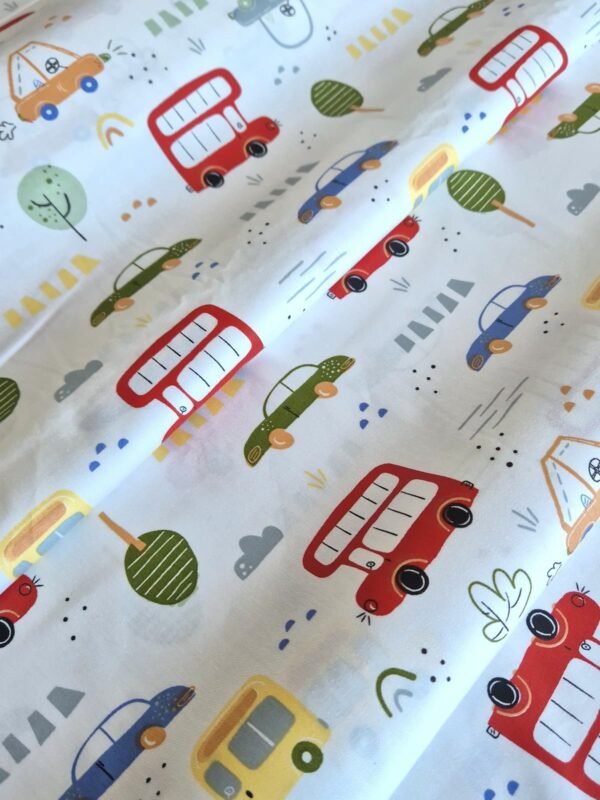 Tela sarga con estampado de autobuses rojos y autos clásicos dispuesta en forma de olas