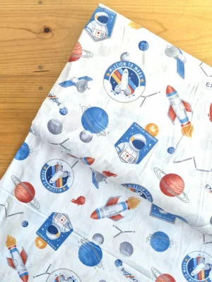 Tela Sarga con diseño de astronautas y cohetes sobre fondo blanco vista desde arriba