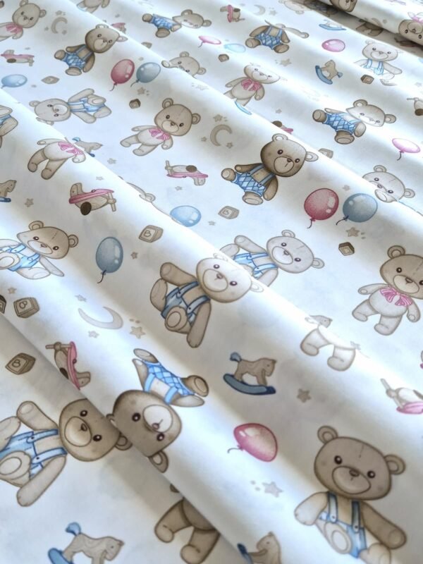 Tela sarga con estampado de osos de peluche bebés y globos dispuesta en forma de olas