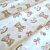 Tela sarga con estampado de osos de peluche rosas y juguetes dispuesta en forma de olas