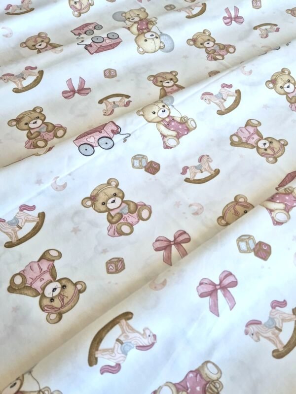 Tela sarga con estampado de osos de peluche rosas y juguetes dispuesta en forma de olas