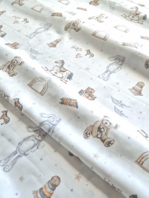 Tela sarga con estampado de osos de peluche y caballitos de juguete dispuesta en forma de olas