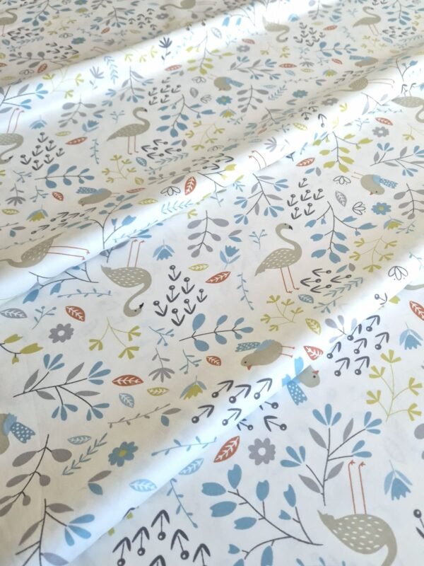 Tela sarga con estampado de flamencos en tono celeste dispuesta en forma de olas