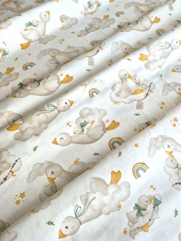 Tela sarga con estampado de cisnes, nubes y arcoíris dispuesta en forma de olas