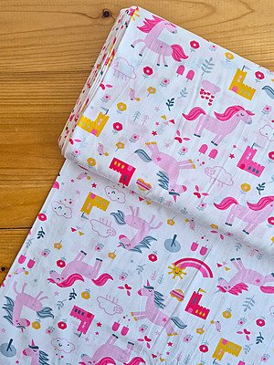 Tela sarga con estampado de unicornios rosas y castillos vista desde arriba