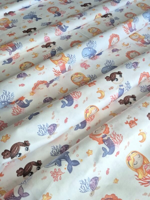 Tela sarga con estampado de sirenas y animales marinos dispuesta en forma de olas