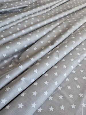 Tela sarga con estrellas en gris claro dispuesta en ondas para mostrar caída y textura