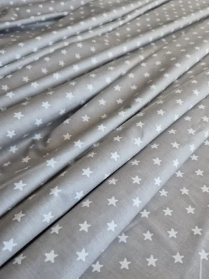 Tela sarga con estrellas en gris claro dispuesta en ondas para mostrar caída y textura