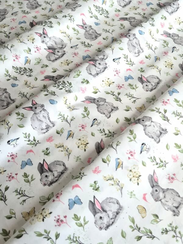 Tela sarga con estampado de conejos y mariposas en el campo dispuesta en forma de olas