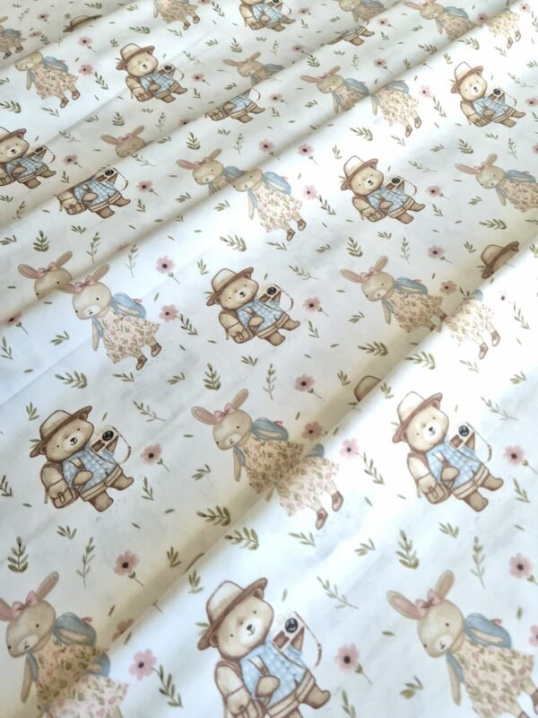 Tela sarga con estampado de conejos y osos viajeros dispuesta en forma de olas