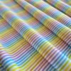Tela sarga con rayas multicolor dispuesta en ondas para mostrar caída y textura