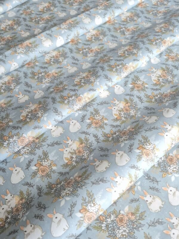 Tela sarga con estampado de conejos y flores sobre fondo celeste dispuesta en forma de olas