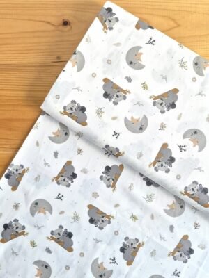Vista superior de tela sarga con estampado de koalas y lunas crecientes sobre fondo claro