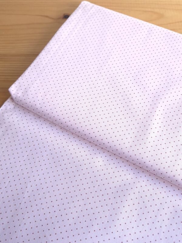 Tela sarga con estampado de lunares mini en rosa pálido vista en ángulo de 45 grados