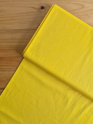 Vista superior de la tela sarga amarilla con lunares blancos