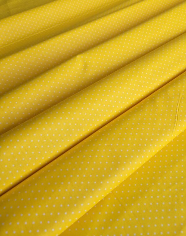 Tela sarga amarilla con lunares blancos dispuesta en ondas para mostrar textura y caída