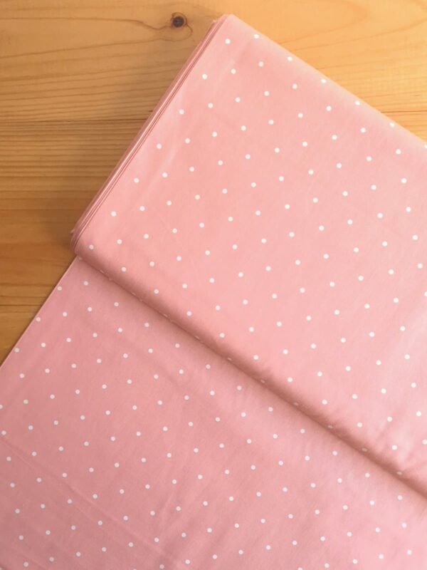 Vista superior de tela sarga color rosa salmón con lunares blancos
