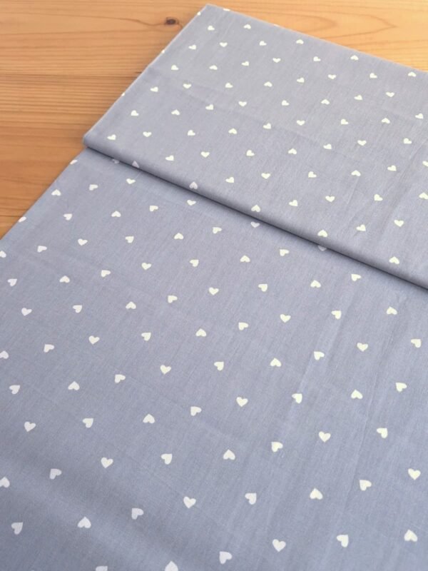 Tela Sarga con corazones blancos sobre fondo gris claro vista en ángulo de 45 grados