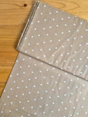 Tela Sarga con corazones blancos sobre fondo beige oscuro vista desde arriba