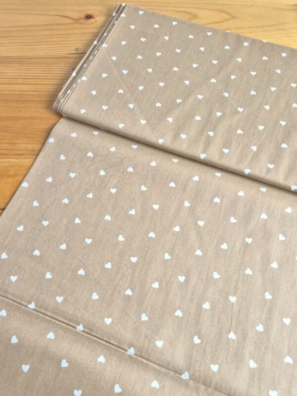 Tela Sarga con corazones blancos sobre fondo beige oscuro vista a 45 grados