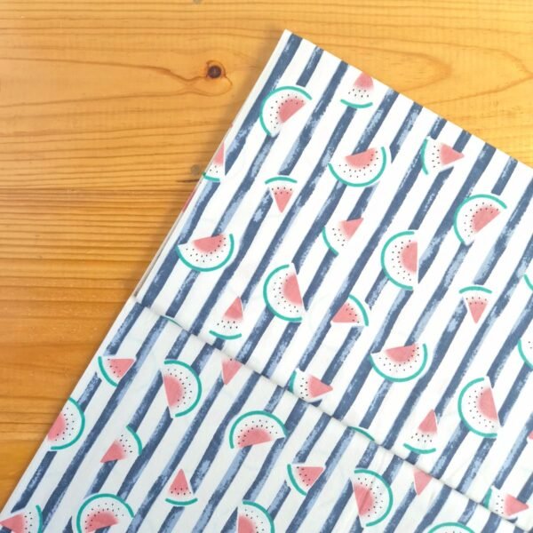 Vista superior de tela sarga con estampado de sandías sobre fondo de rayas azules