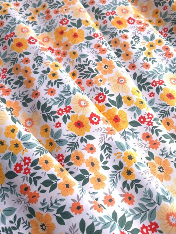 Tela Sarga con flores amarillas y naranjas en fondo blanco doblada en forma de olas