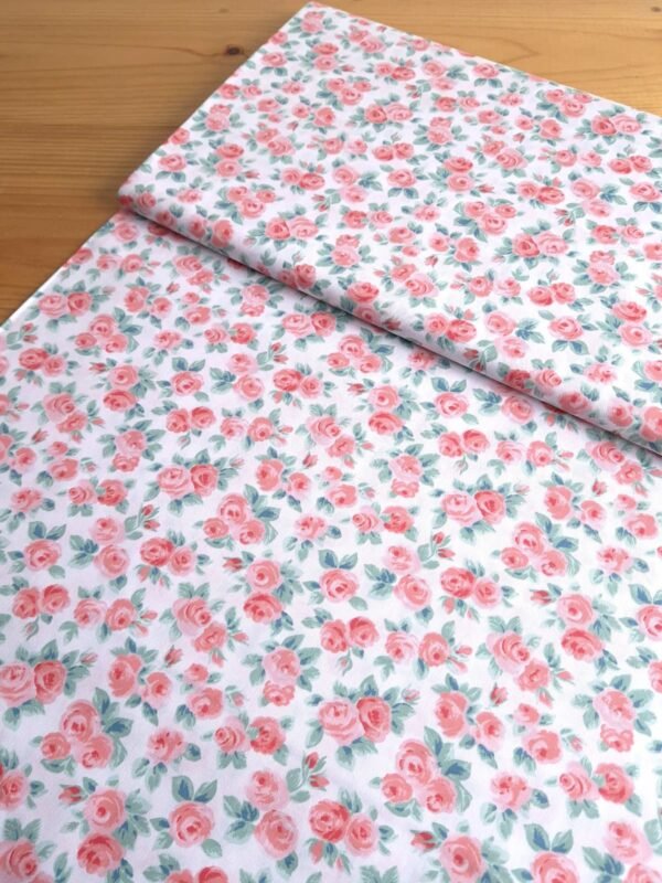 Tela Sarga con rosas rojas y hojas verdes sobre fondo blanco vista en ángulo de 45 grados