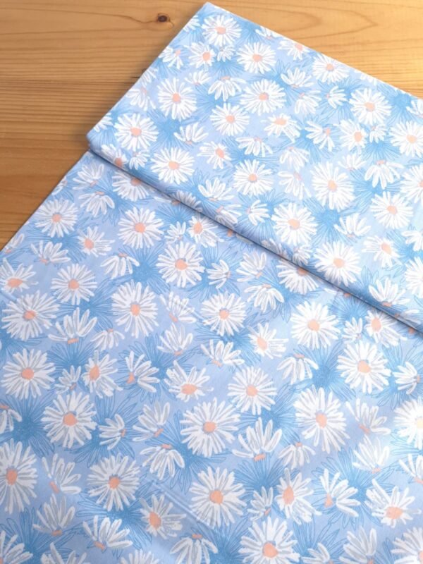 Tela Sarga con margaritas blancas sobre fondo celeste vista en ángulo de 45 grados