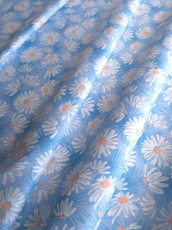 Tela Sarga con margaritas blancas en fondo celeste doblada en forma de olas