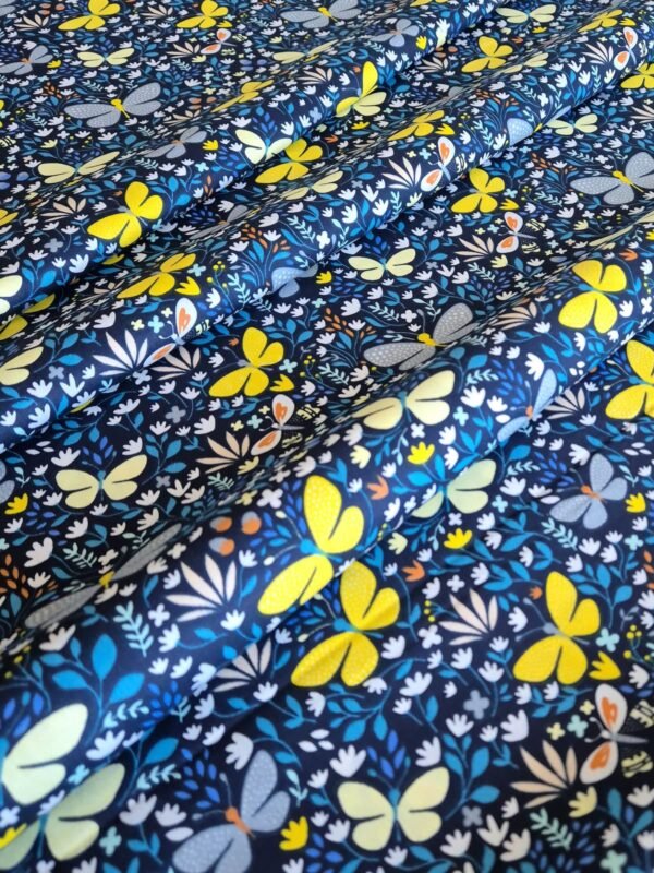 Tela sarga con estampado de mariposas amarillas sobre fondo azul oscuro dispuesta en forma de olas