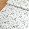 Tela sarga blanca con estampado de mariposas y hojas, vista en ángulo para mostrar textura y volumen