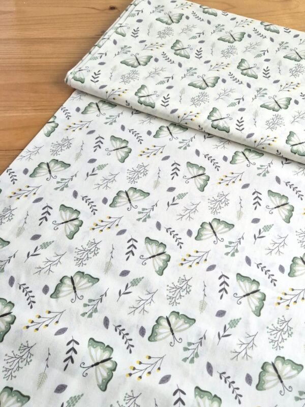 Tela sarga blanca con estampado de mariposas y hojas, vista en ángulo para mostrar textura y volumen