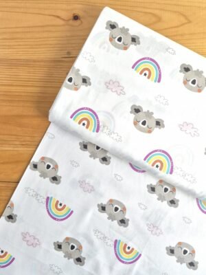Vista superior de tela sarga con estampado de koalas, arcoíris y nubes sobre fondo blanco