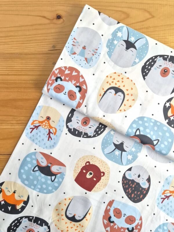 Vista superior de tela sarga con estampado de caras de animales en círculos sobre fondo blanco