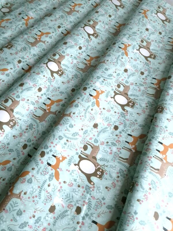 Tela sarga con estampado de ciervos, zorros y osos del bosque dispuesta en forma de olas