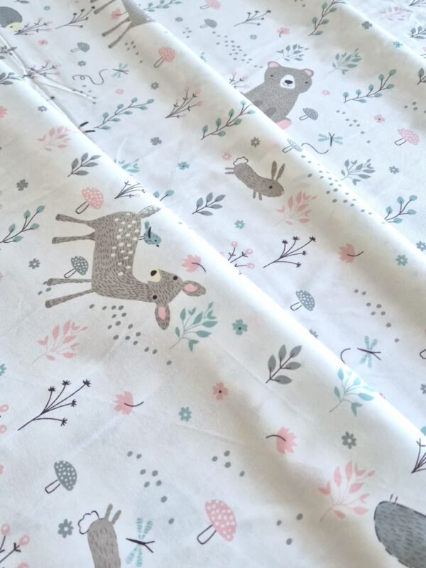 Tela sarga con estampado de oso y ciervo con flores sobre fondo blanco dispuesta en forma de olas