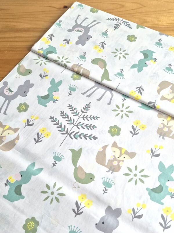 Tela sarga con estampado de animales del bosque en tono verde vista en ángulo de 45 grados