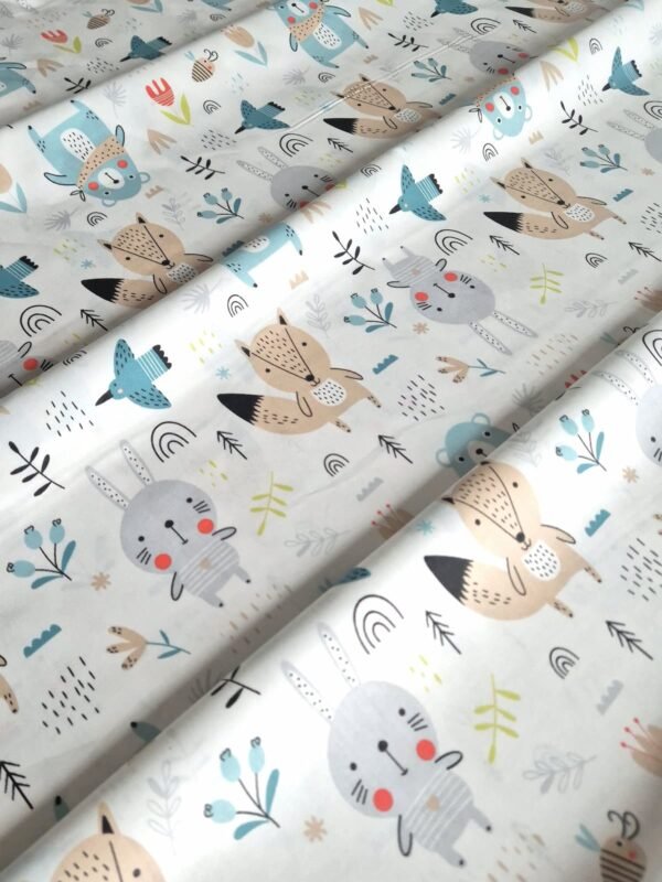 Tela sarga con estampado de osos y animales en tonos pastel dispuesta en forma de olas