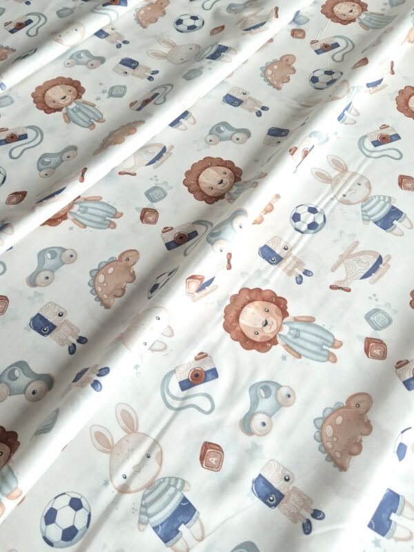 Tela sarga con estampado de leones, dinosaurios y juguetes para bebé dispuesta en forma de olas