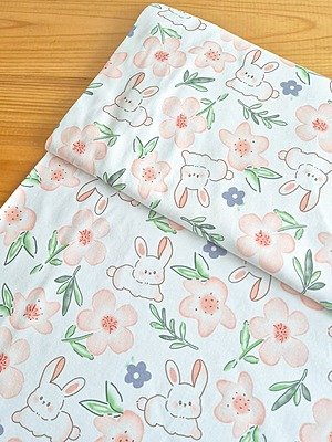 Tela interlock, tela algodón suave con estampado de conejos y flores en tonos naranjas para confección de ropa infantil y manualidades en Chile