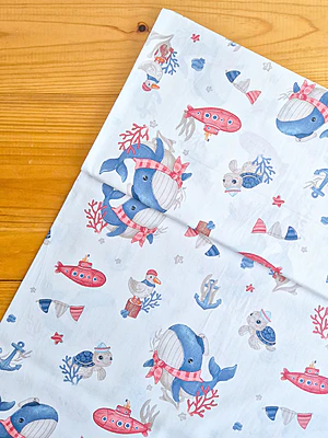 Tela sarga (tela crea), tela de algodón con estampado de ballenas, tortugas y submarinos sobre fondo blanco, ideal para confección y manualidades en Chile.