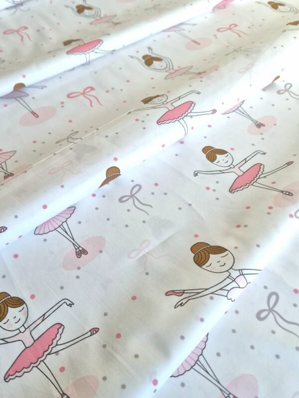 Tela sarga con estampado de bailarinas y lazos rosados dispuesta en forma de olas