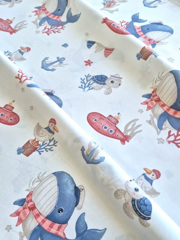 Tela sarga con estampado de ballenas, tortugas y submarinos dispuesta en forma de olas