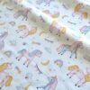 Tela sarga con estampado de unicornios y arcoíris en tonos rosas dispuesta en forma de olas