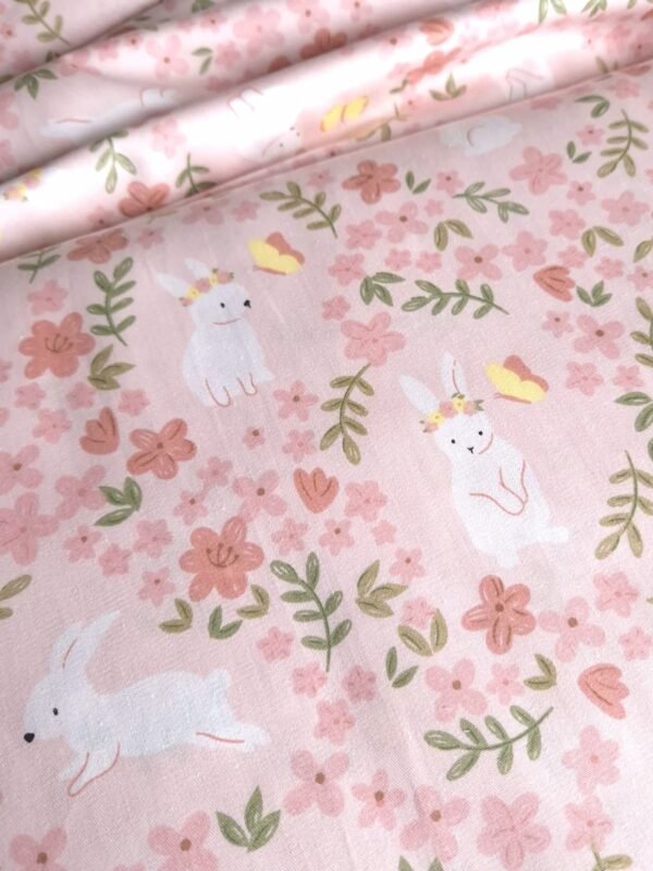 Tela sarga con estampado de conejos y mariposas en campo de flores en forma de olas